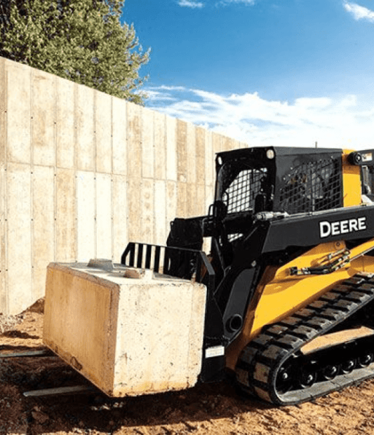 A skid-steer setting a concrete block